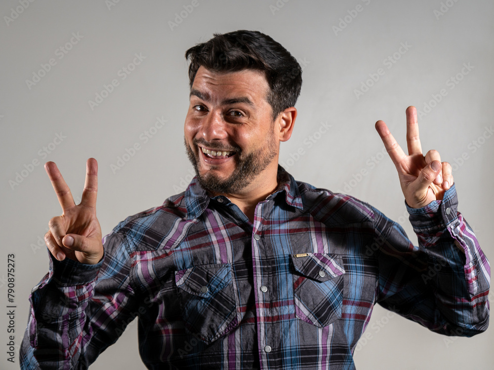 Naklejka premium Hombre feliz haciendo una V con sus manos en señal de victoria y triunfo. Fotografía de estudio con fondo blanco