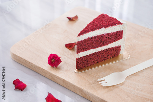 Red velvet cake on a cutting board and flower petals.