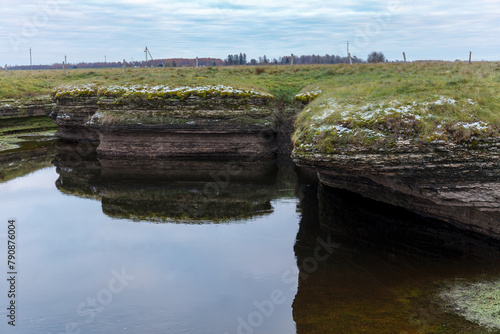 Rock outcrops (karst) and hills in Kostivere against the cloudy sky, early winter, frost on stones. Estonia.