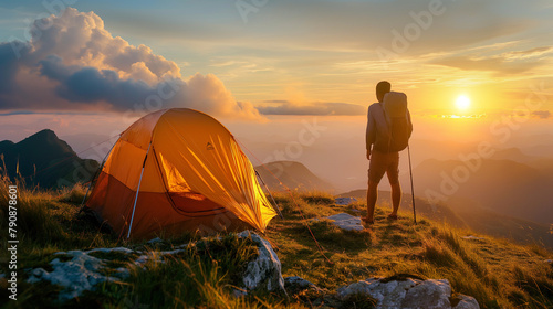 Climbers with backpacks relax on top of mountain and enjoy cliff sunrise with mountain scenery in the background. Sunny day and blue sky