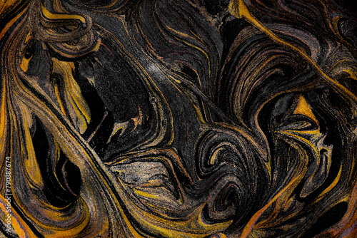 Closeup of gold and black fluid metallic paint textured background