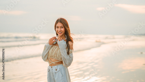 Relax asian woman wearing headphones listening to music breathing fresh air enjoying beautiful sunset over the sea beach, copy space.