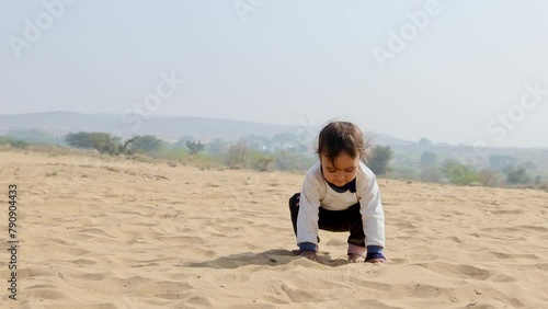 innocent toddler playing with sand at desert at day from flat angle photo