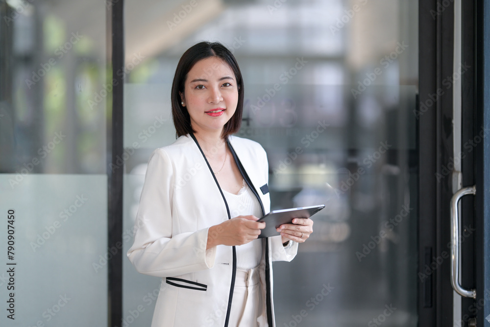 Smiling professional businesswoman holding a tablet in a contemporary office setting