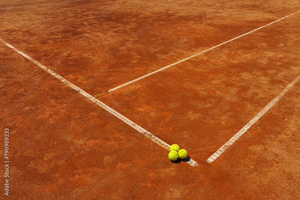  A yellow tennis balls lies on the clay court.