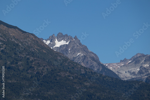 Lonely horizontal view of mountain peak with growing vegetation on the bottom, and an infinite clear blue sky on top