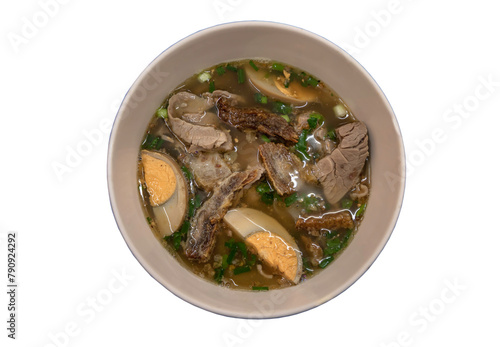 Rolled rice noodles in five-spices broth (Guay Jub) ingredients are boiled eggs, crispy pork and pork in brown stewed soup in white bowl isolated on white background with clipping path.