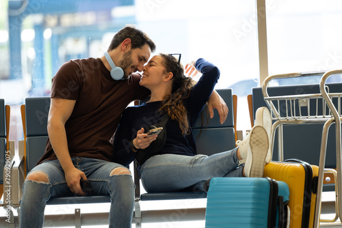 couple sitting lovingly at the airport waiting for their flight to depart photo