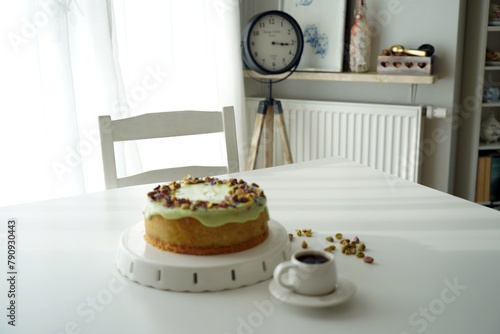 Ciasto, sernik, tort, pistacje z kawą na stole w kuchni © Ilona