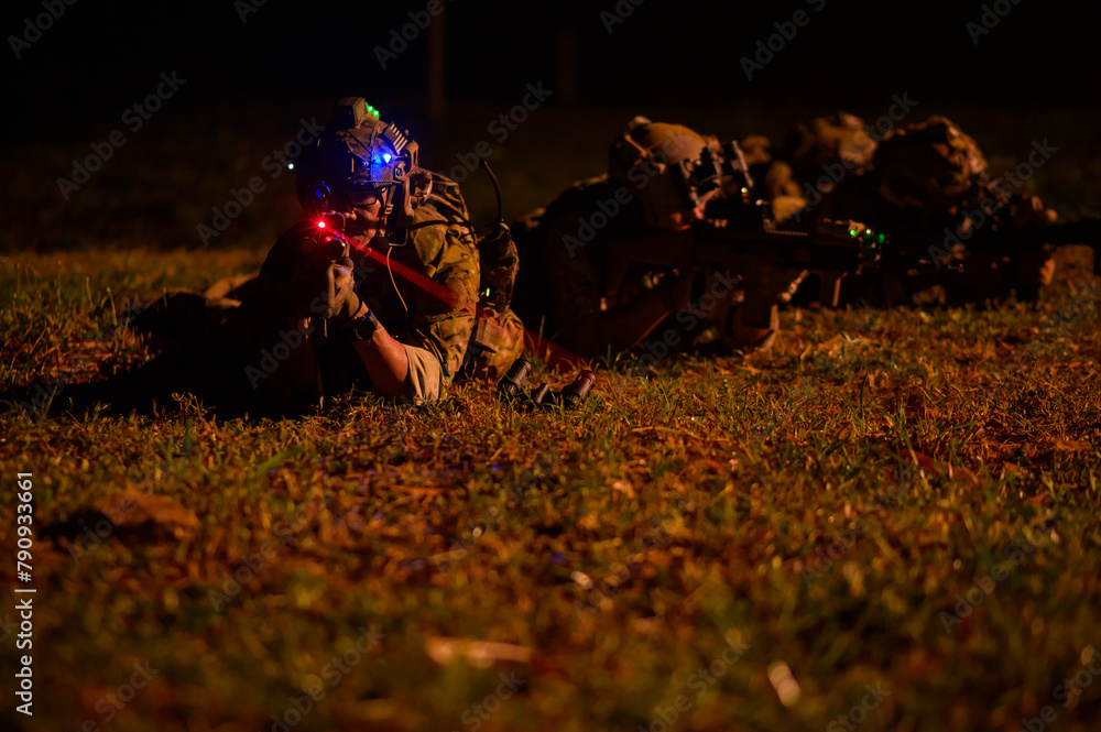 Fototapeta premium Soldiers in camouflage uniforms aiming with their rifles.ready to fire during Military Operation at night, soldiers training in a military operation