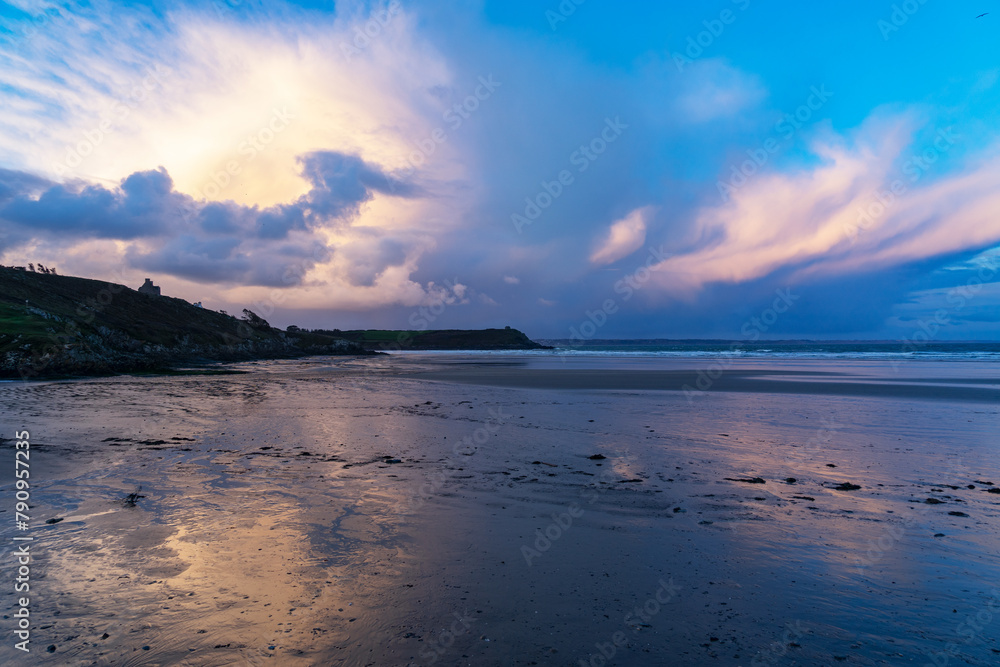Les premières lueurs du jour teintent la plage de Lestrevet, Finistère, Bretagne, de douces nuances rosées et bleutées, créant des reflets enchanteurs sur le sable humide.