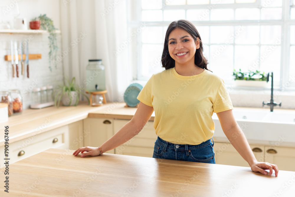 Smiling woman standing in a sunny kitchen Smiling woman standing in a sunny kitchen