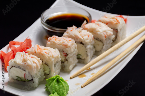 Enjoy a plate of sushi with chopsticks and a bowl of soy sauce