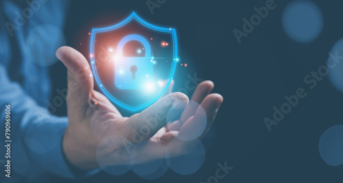 Businessman holding on virtual screen shield with master key icon for input password to internet access. Technology protects privacy encryption for cybersecurity networks and user security concepts.