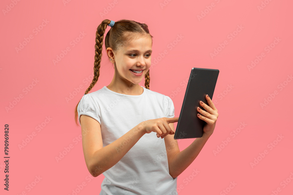 Smiling girl using tablet on pink background Smiling girl using tablet on pink background
