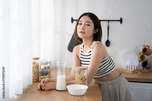 Asian woman in cozy and comfortable clothes sitting on kitchen counter while picking up some beans. Healthy living home and domestic life. Rich nutrition lifestyle