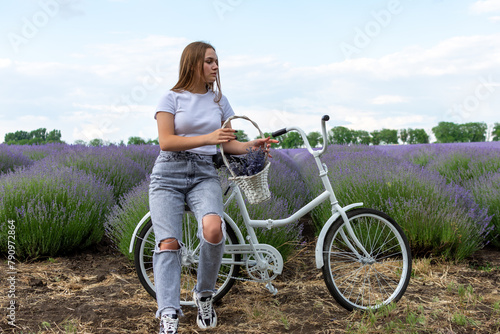 Woman on white bicycle amidst lavender field under blue sky