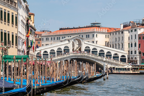 Group of gondolas moored in channel Canal Grande with scenic view of famous Rialto bridge in city of Venice, Veneto, Northern Italy, Europe. Venetian architectural landmarks. Romantic vacation © Chris