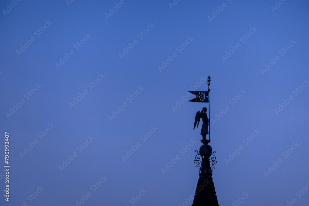 View of isolated marble statue of the Milan Cathedral (Duomo di Milano) seen from rooftop, Milan, Lombardy, Italy, Europe. Historical facade with spires. Gothic architecture features. Blue background