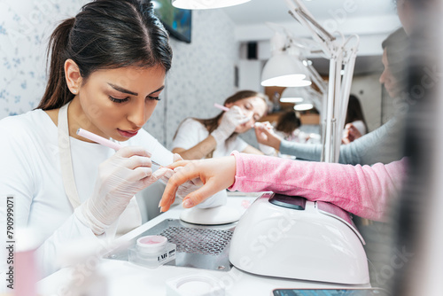Professional manicurists working in a modern beauty salon. Satisfied female clients receiving nail manicure treatments at spa center.