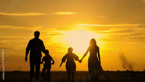 Dad, Mom teaches children to ride bike, sunset. Childhood dream of riding bike. Family walk, mom dad, child, parental support. Father teaches his child to keep balance while sitting on bicycle. Kids