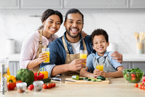 Positive African American father mother and son drinking juice
