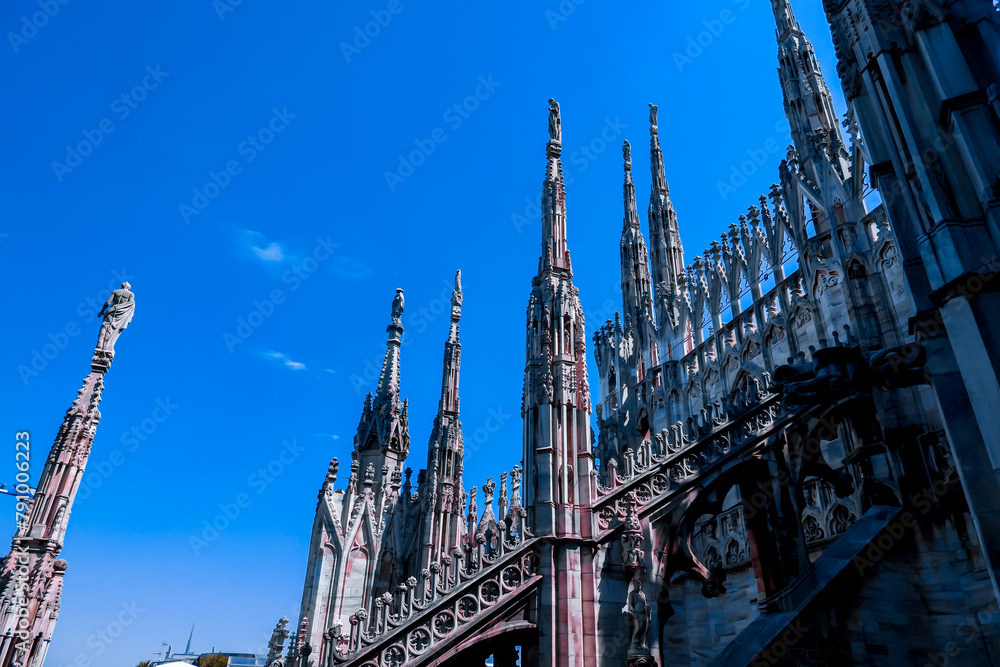 External view of Milan Cathedral (Duomo di Milano) from the rooftop, Milan, Lombardy, Italy, Europe. Historical marble facade with spires. Gothic architecture features. City travel tourism External view of Milan Cathedral (Duomo di Milano) from the rooftop, Milan, Lombardy, Italy, Europe. Historical marble facade with spires. Gothic architecture features. City travel tourism