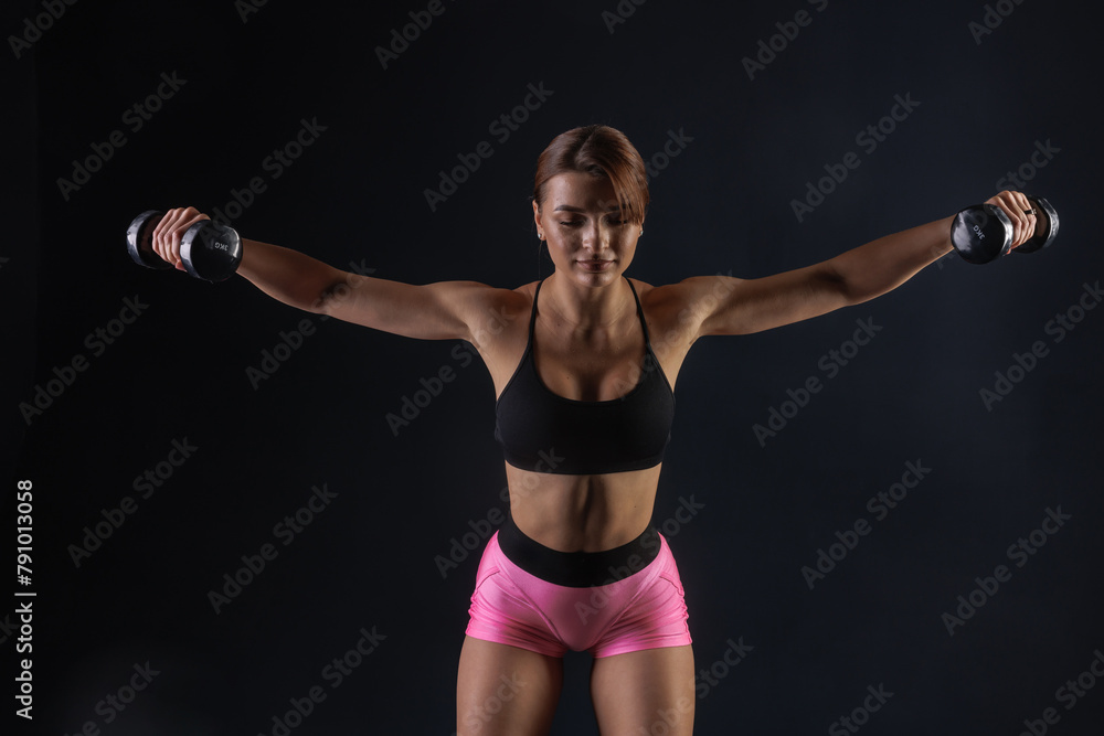 athletic girl doing exercise with dumbbells on black background, sports concept