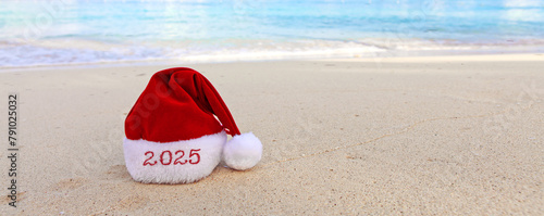 New Year 2025 background with red Santa hat on Caribbean beach.