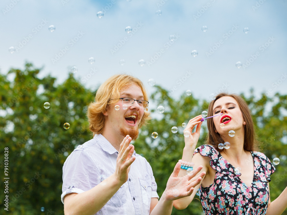 Fototapeta premium Couple blowing soap bubbles, having fun
