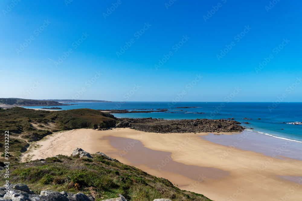 Vue depuis le sommet des falaises sur la plage de sable de la Fosse, sous un ciel bleu immaculé, dans les Côtes d'Armor.