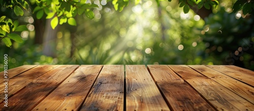 An unfurnished wooden patio table surrounded by blurred foliage in the background, suitable for displaying products. photo
