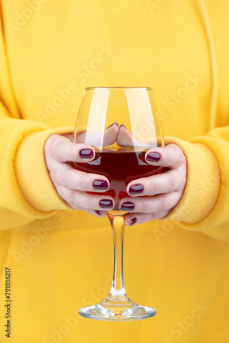 Female hands with fashionable manicure holding a glass of red wine.