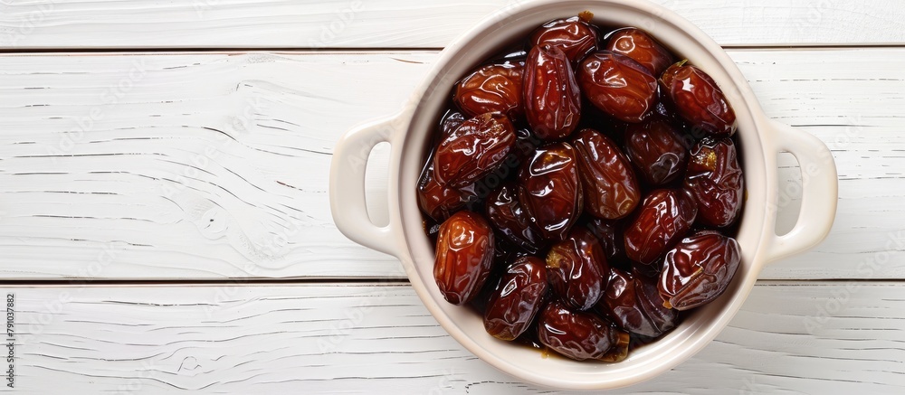 Top view of a dish filled with pitted dates placed on a white wooden surface. Top view of a dish filled with pitted dates placed on a white wooden surface.