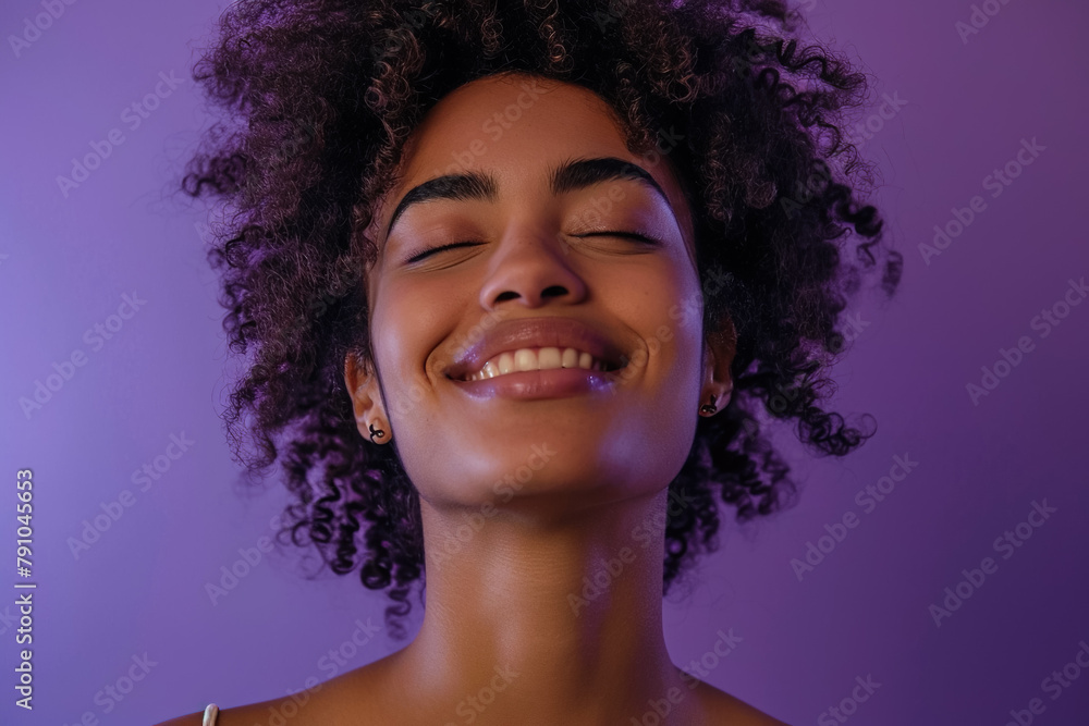 A woman with her eyes closed and a smile on a purple background A woman with her eyes closed and a smile on a purple background