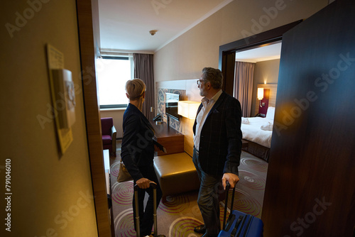 Adult businessman and businesswoman standing and looking inside hotel room