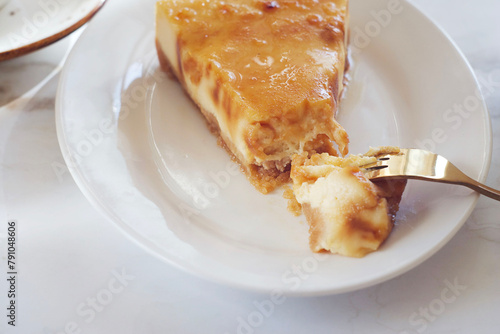 Piece of cheesecake with caramel in a plate on a marble table