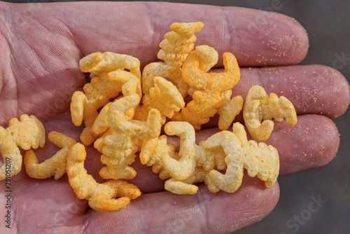 a bunch of small yellow chips in the shape of crustaceans lie on the palm