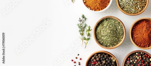 Assortment of spices in bowls placed on a white background. Overhead view with blank space for text.