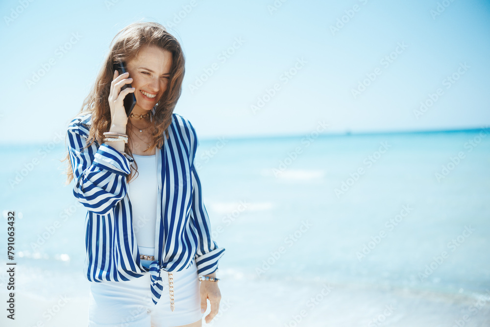 happy stylish woman on ocean shore talking on smartphone happy stylish woman on ocean shore talking on smartphone