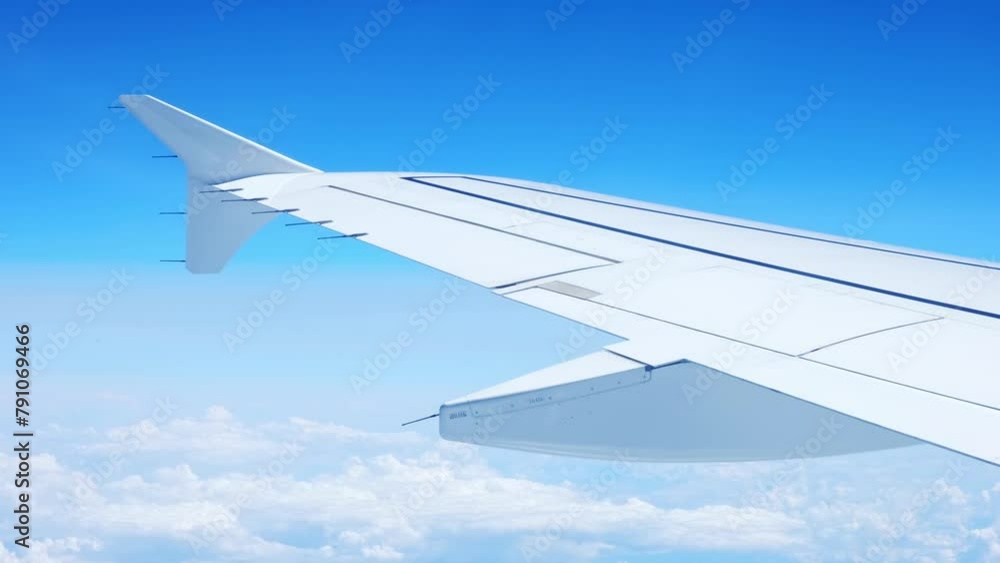 View of an airplane wing from a porthole against a blue sky background. A passenger plane flies above the clouds in the morning light. The concept of traveling by air. Fear of heights, aerophobia. 4K View of an airplane wing from a porthole against a blue sky background. A passenger plane flies above the clouds in the morning light. The concept of traveling by air. Fear of heights, aerophobia. 4K