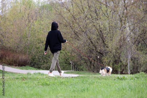 Girl walking a dog in city park. Lady with pet in spring