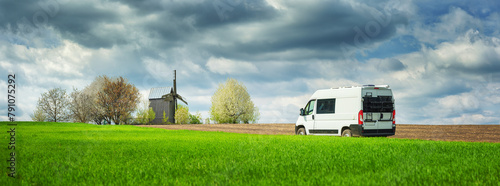 panorama with green field and white camper bus