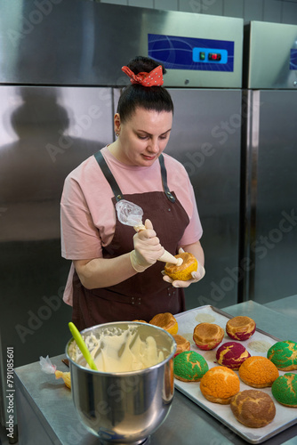 Woman confectioner adding creamy or cheese filling into the choux au craquelin photo