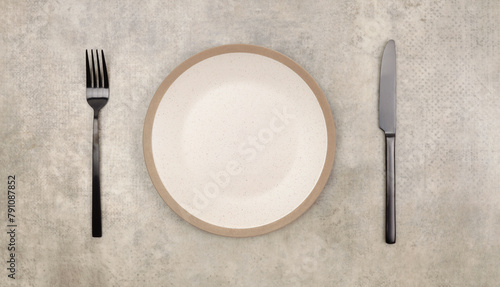 Empty beige gray plate, fork; knife on marble rustic concrete background. Top view, flat lay.