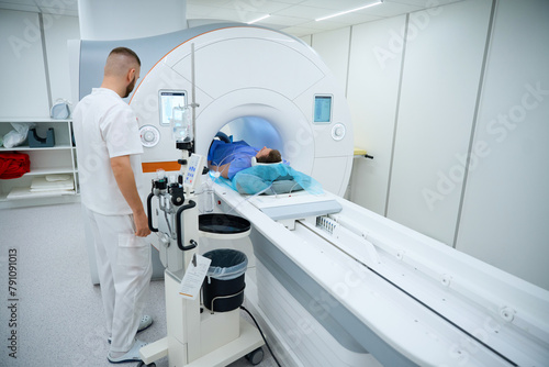 Doctor preparing man for knee magnetic resonance imaging procedure