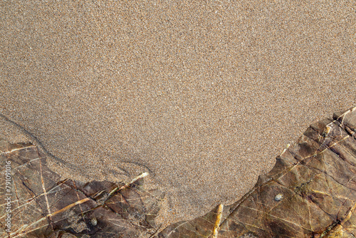 Smooth untouched fine sand and sandy rocks on a beach on a sunny day, viewed from above. Abstract textured natural sandy background, top view. Copy space.