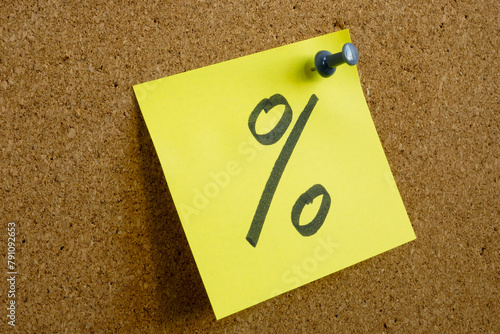 A note with a percent sign as a symbol of profit is pinned to an office board.