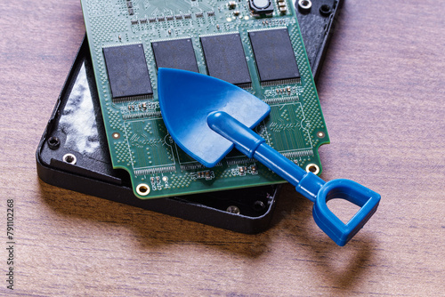 Opened SSD and blue shovel. Cryptocurrency mining concept © Yingko