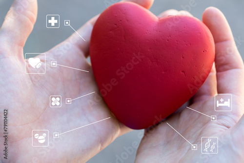 Doctor holds a heart in his hand and shows medical icons on the virtual panel. Healthcare concept.